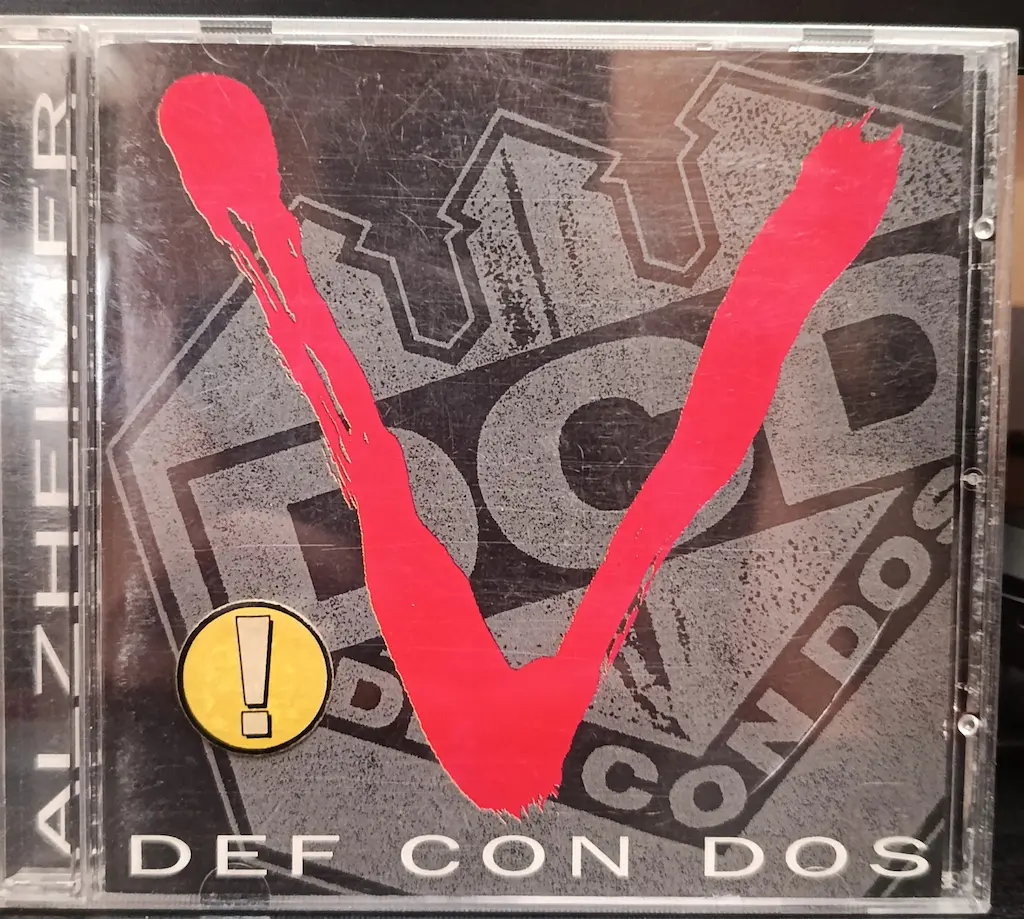 Personal copy of Def Con Dos’s 1995 Alzheimer CD, with a large red V across the cover.